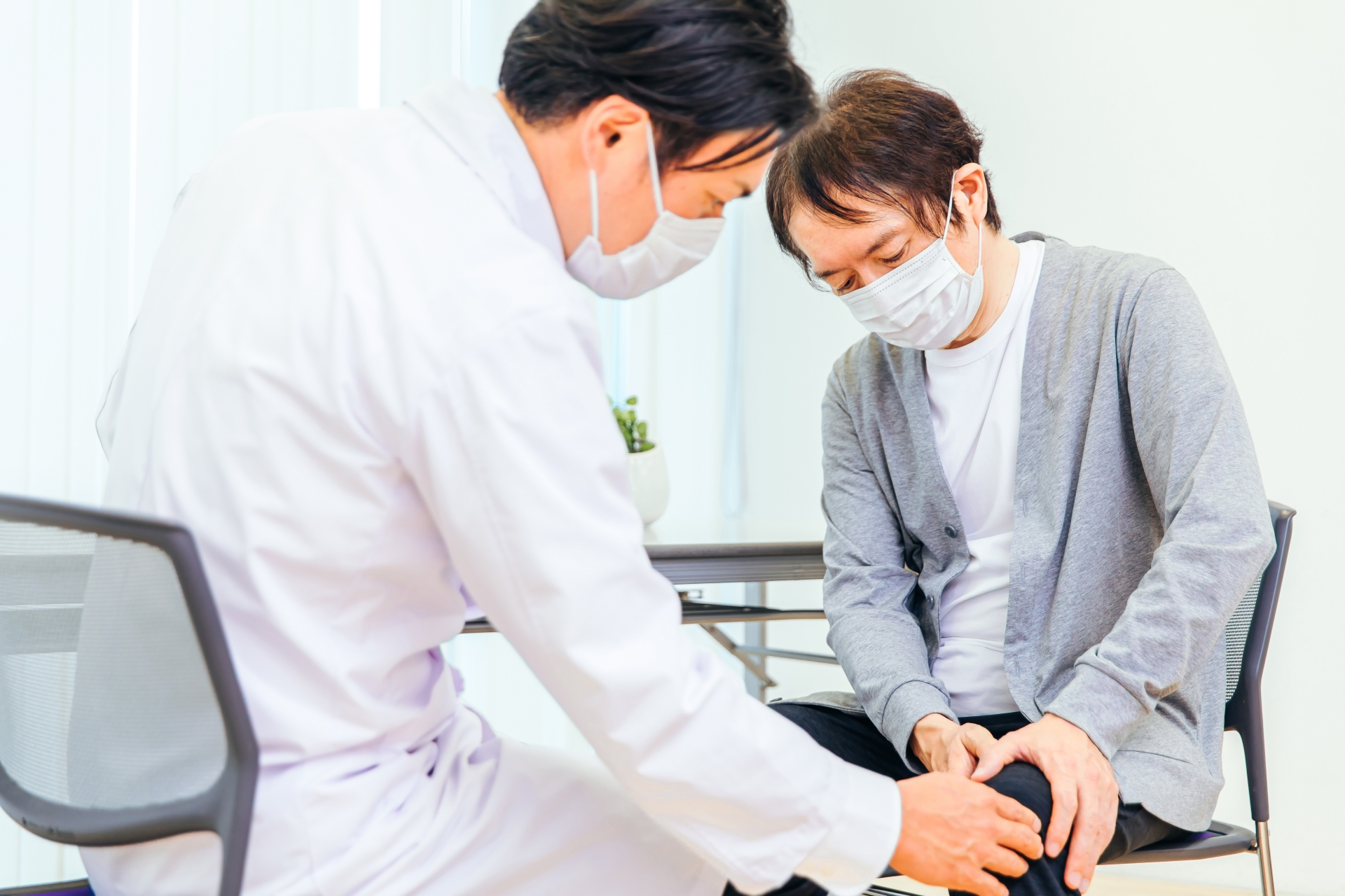 医師が患者の膝関節を診察している