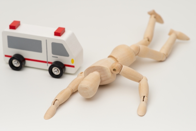 交通事故後に倒れた人形と救急車——遅発性症状のイメージ