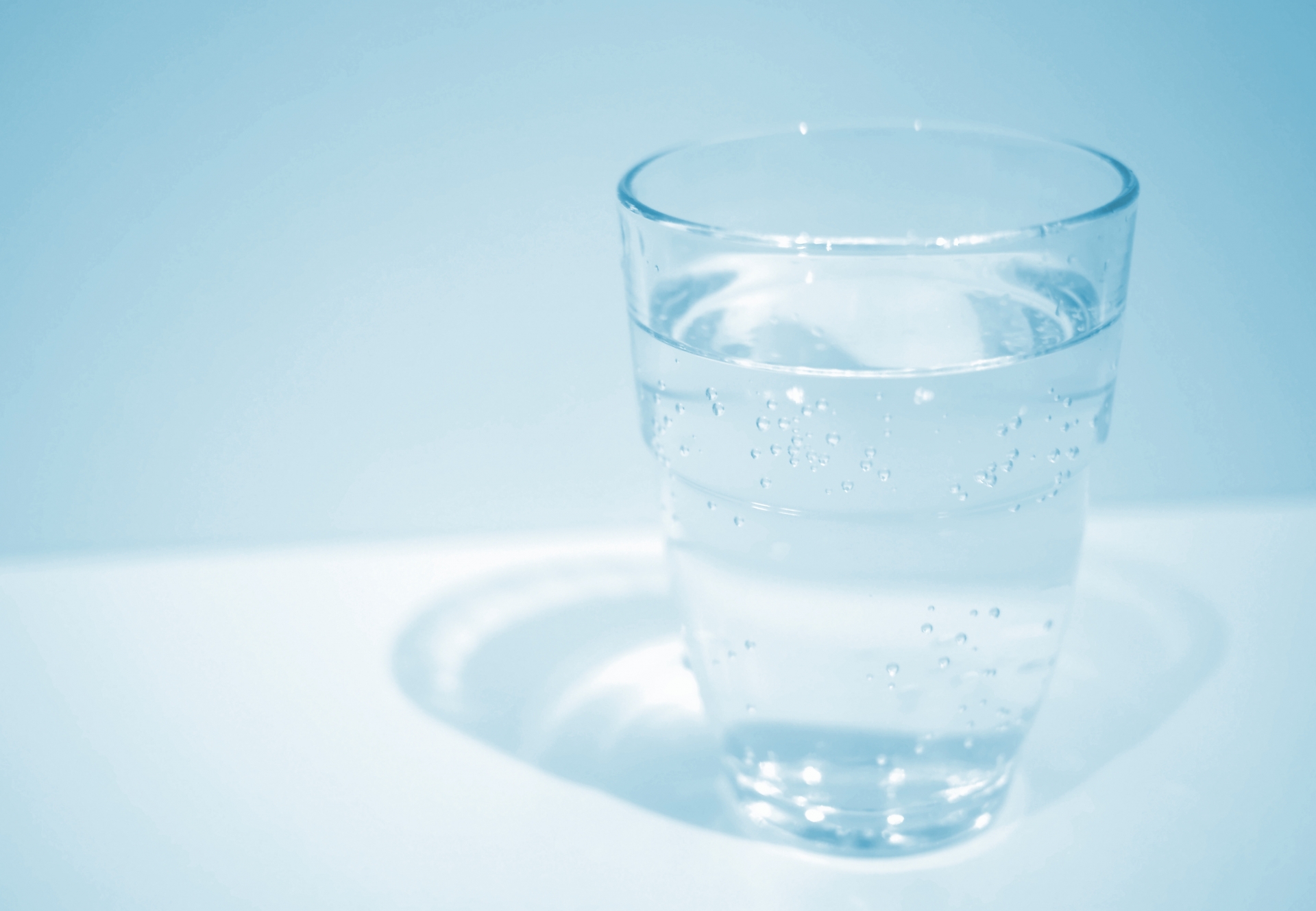 自然の清流のそばに置かれたコップ——ミネラルを含む天然水のイメージ