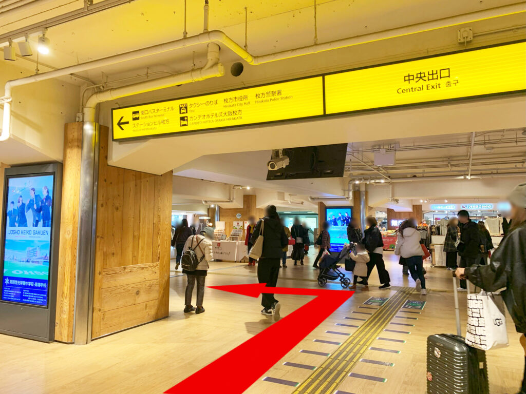 STEP 01: 京阪電車本線 枚方市駅 中央出口を出たのち、上部に見える黄色の「中央出口案内板」を越えて左折します。